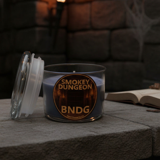 An open candle jar with "Smokey Dungeon"-scent on a stone table with a spell book on a stone table in a dungeons and dragons style fortress room