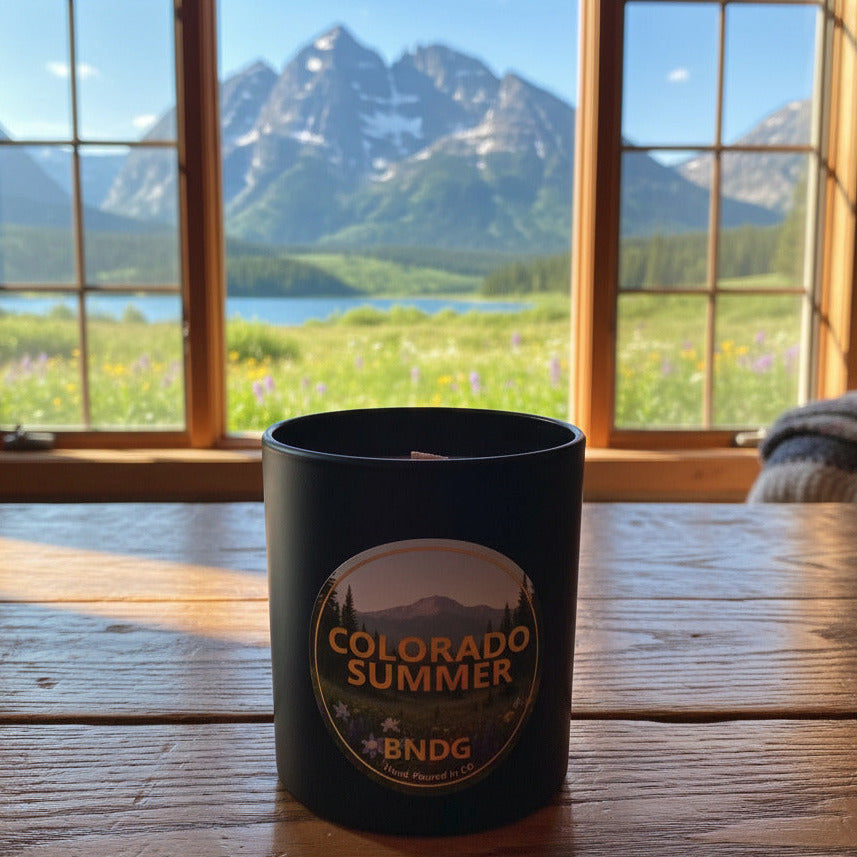 Black candle jar with "Colorado Summer"-scent and a lake with the Maroon Bells in the distance 