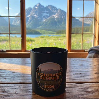 Black candle jar with "Colorado Summer"-scent and a lake with the Maroon Bells in the distance 
