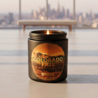 Black Candle jar with "Colorado Fall"-scent in a minimalist room with a big city skyline in the distance