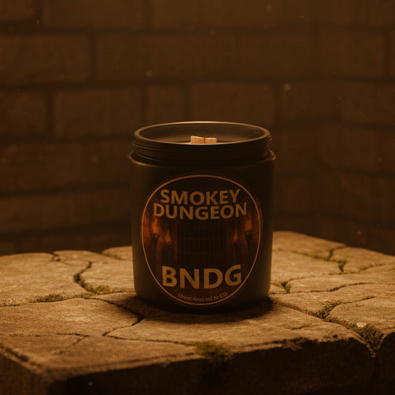 black candle jar with "Smokey Dungeon"-scent on a stone table and masonry brick wall as background
