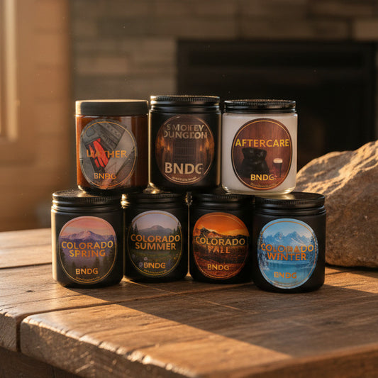 7 candle jars on a wooden table with a fireplace in the background
