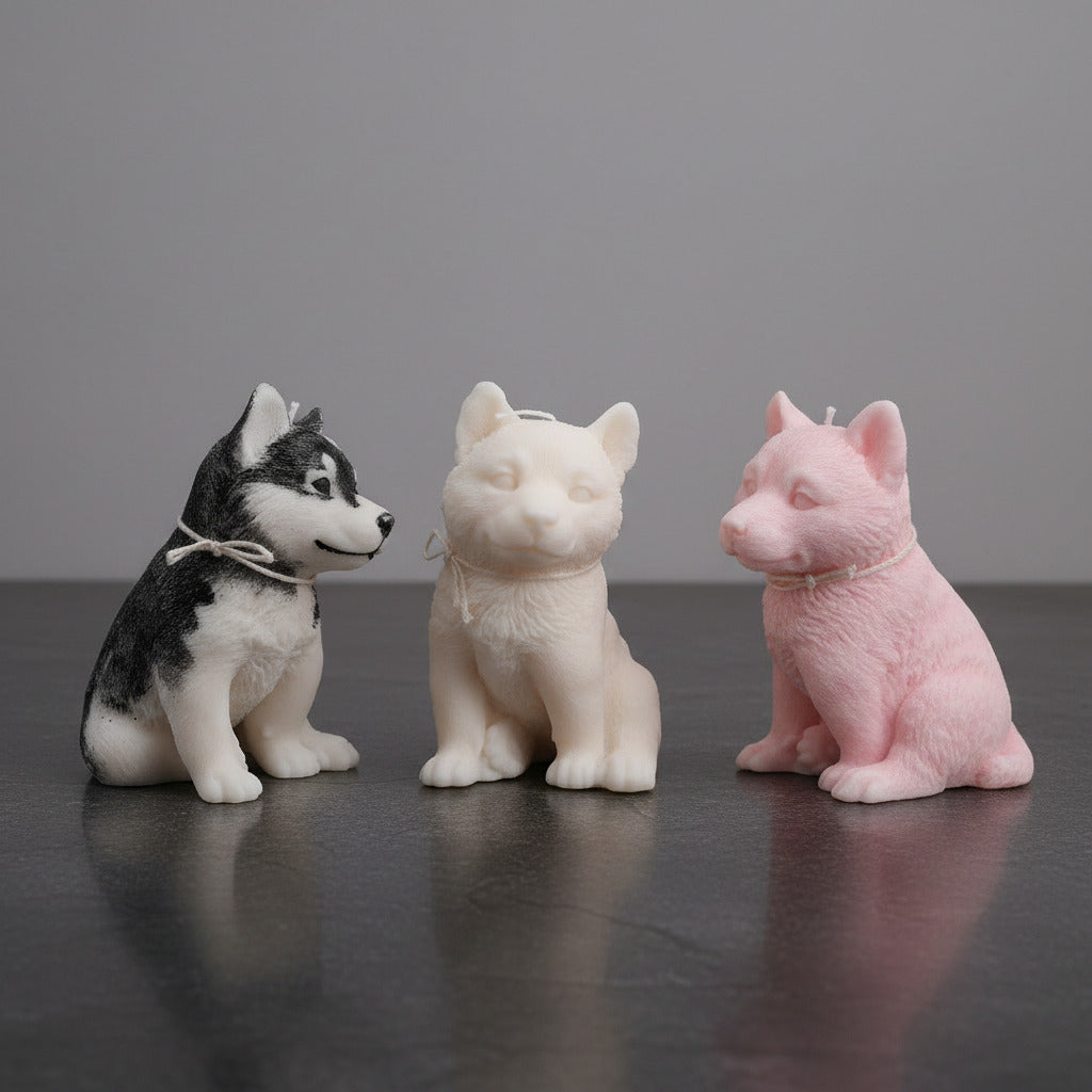 3 different colored husky puppy candles on a stone surface with a gray background