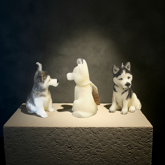 2 painted husky puppy candles on each side of a untainted version of that husky candle sitting on a stone block