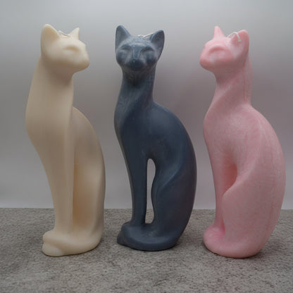 three modern cat candles, (white, dark grey, pink) on a stone surface with grey background