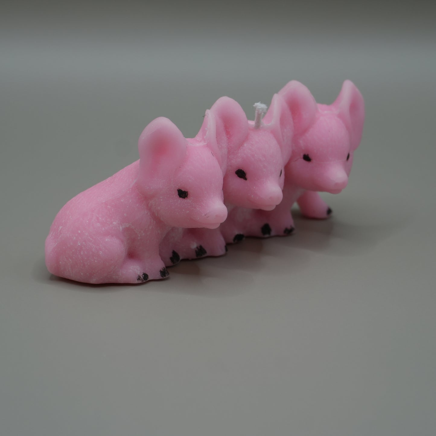 3 little piggies candle from the side with grey background
