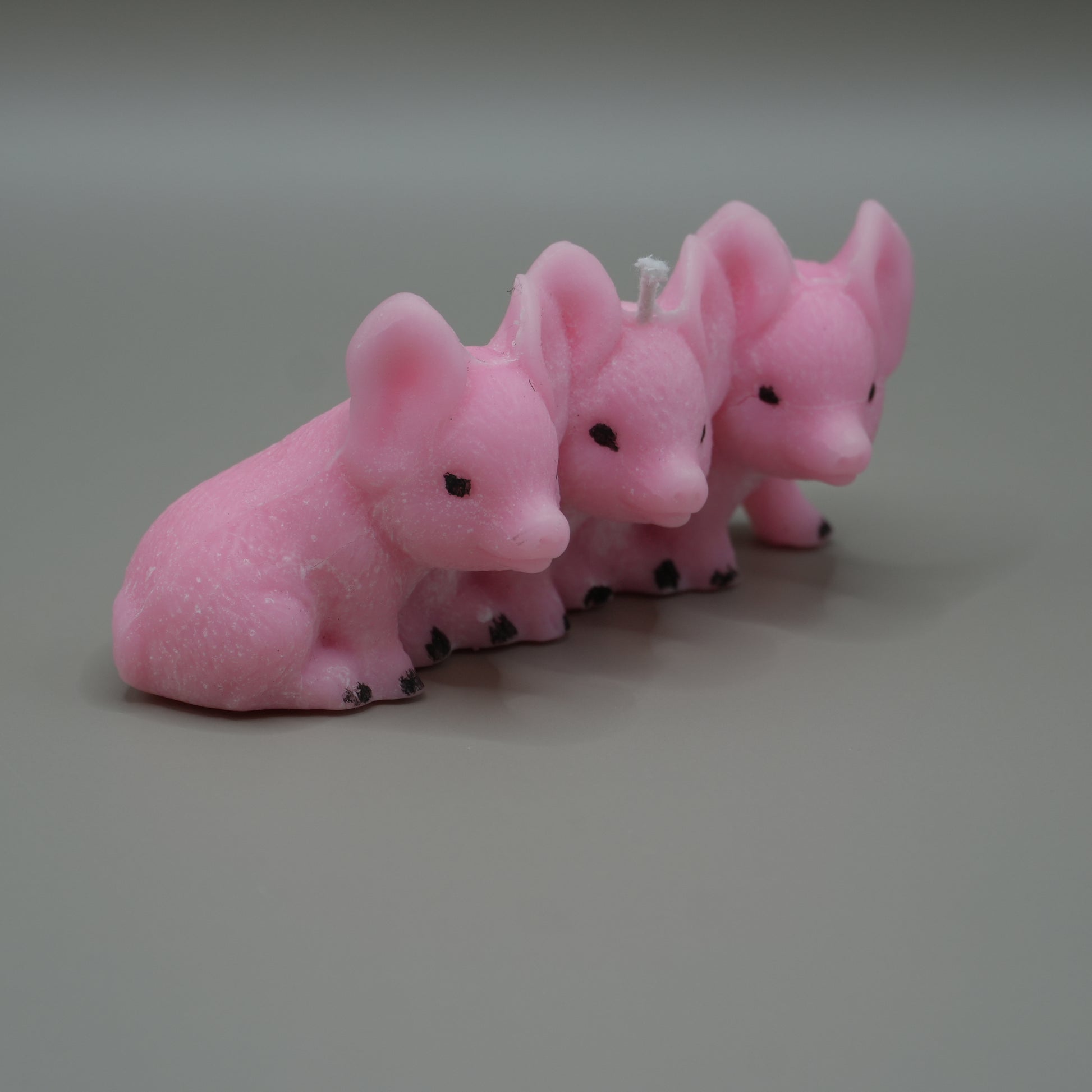 3 little piggies candle from the side with grey background
