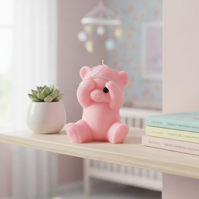 a pink peek-a-boo bear candle on a shelf in a nursery