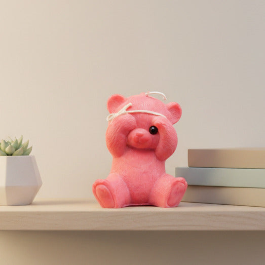 red peek-a-boo teddy bear candle on a shelf