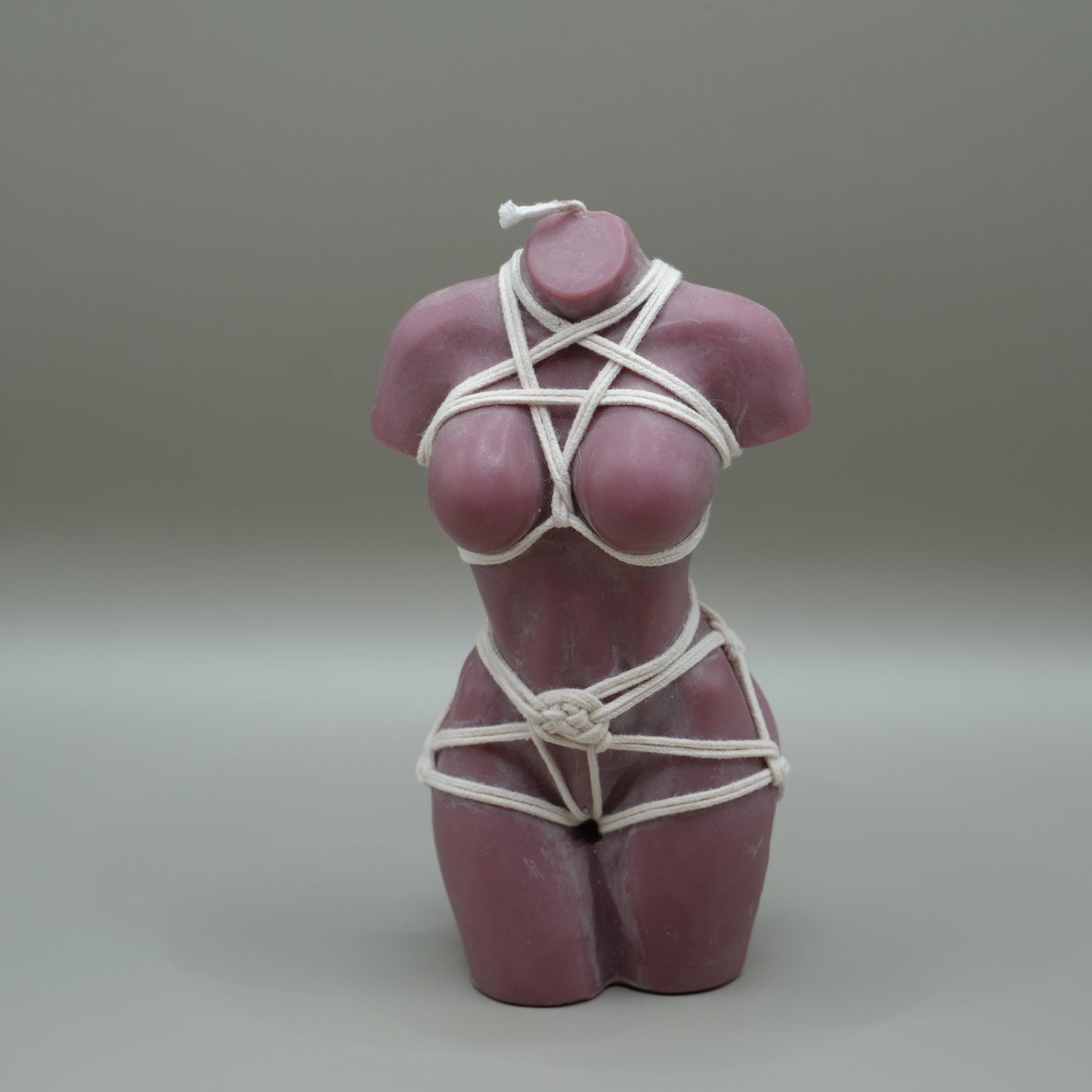 brown female torso candle with white shibari rope harness with grey background
