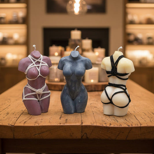 Three female torso candles on a wooden table in a candle store