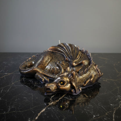 a gold hand-painted lazy dragn candle on black marble