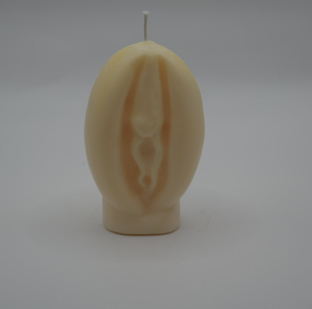 a white vagina-shaped candle on a grey background