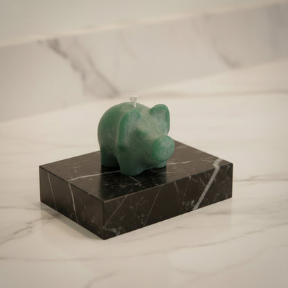 green tiny pig candle (1.5") on black marble block on white counter