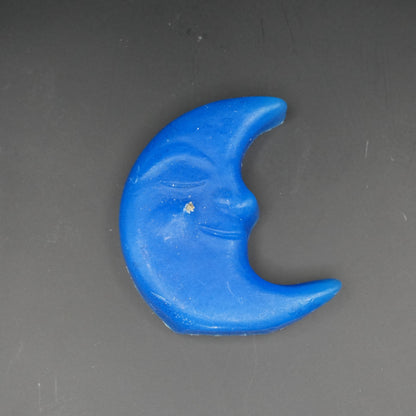 Blue moon-shaped floating candle on a grey surface