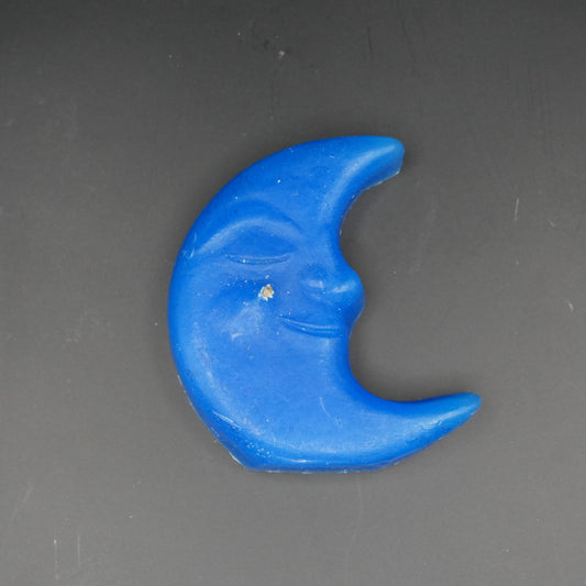 Blue moon-shaped floating candle on a grey surface