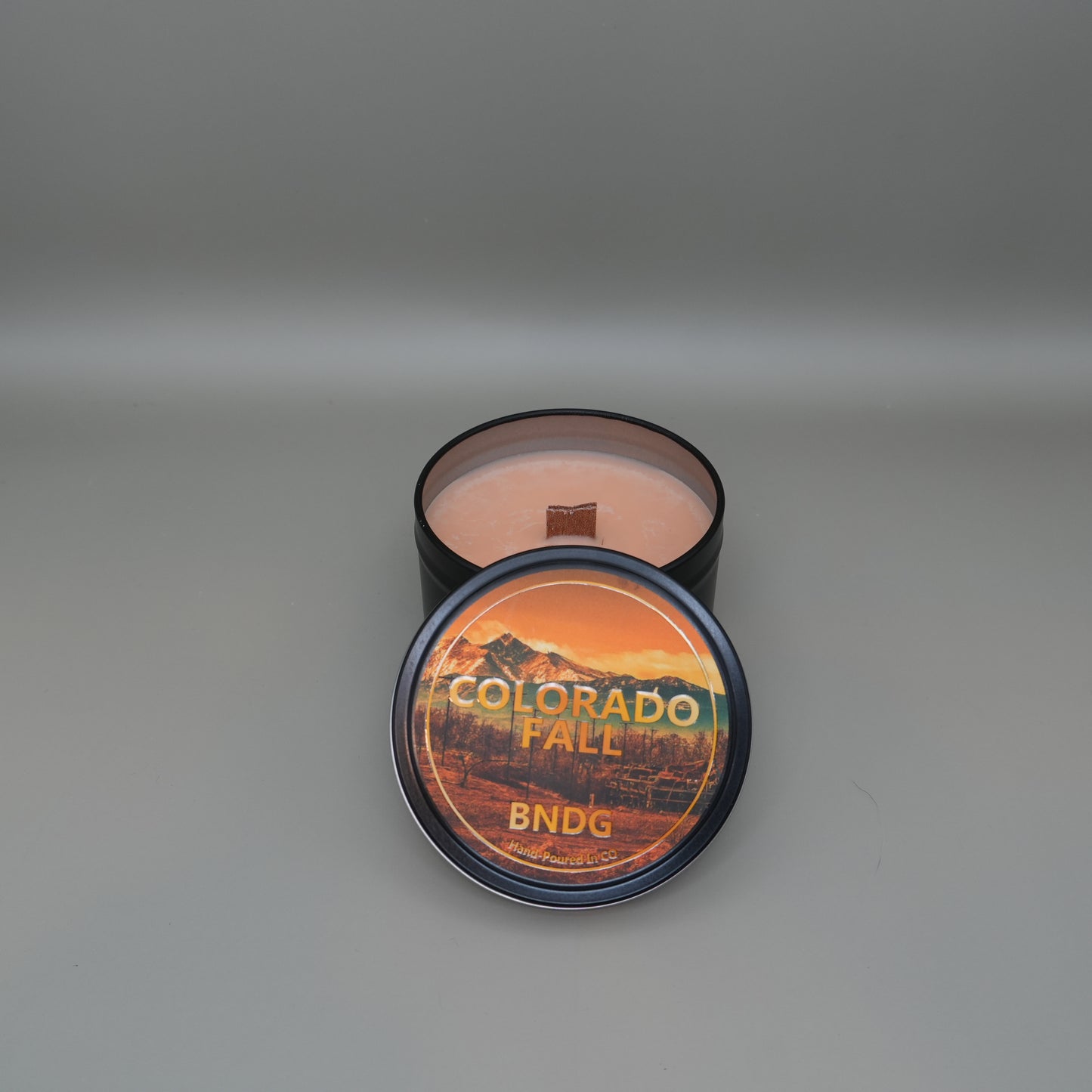 a candle tin with "Colorado Fall"-scent on a gray background