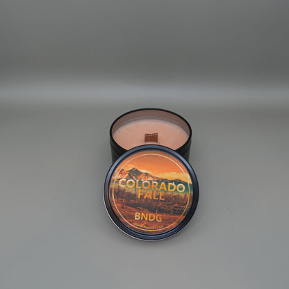 a candle tin with "Colorado Fall"-scent on a gray background