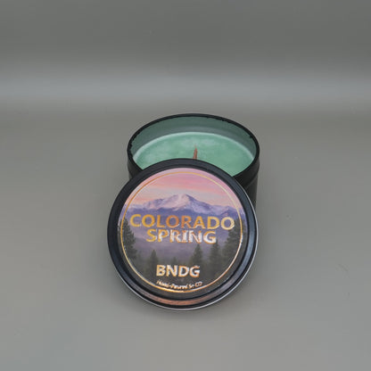 Candle tin with "Colorado Spring"-scent with a gray back ground