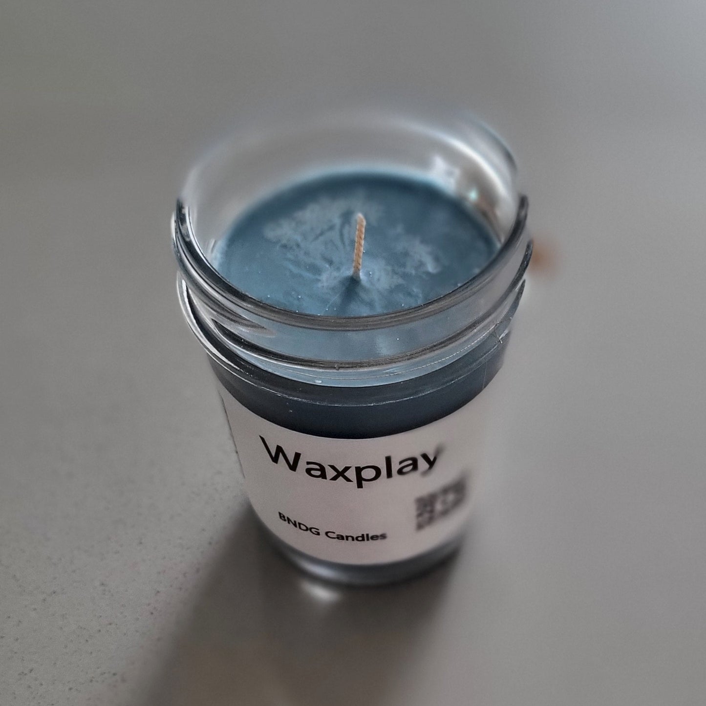 Small container of blue wax with a visible brand label on a light gray background