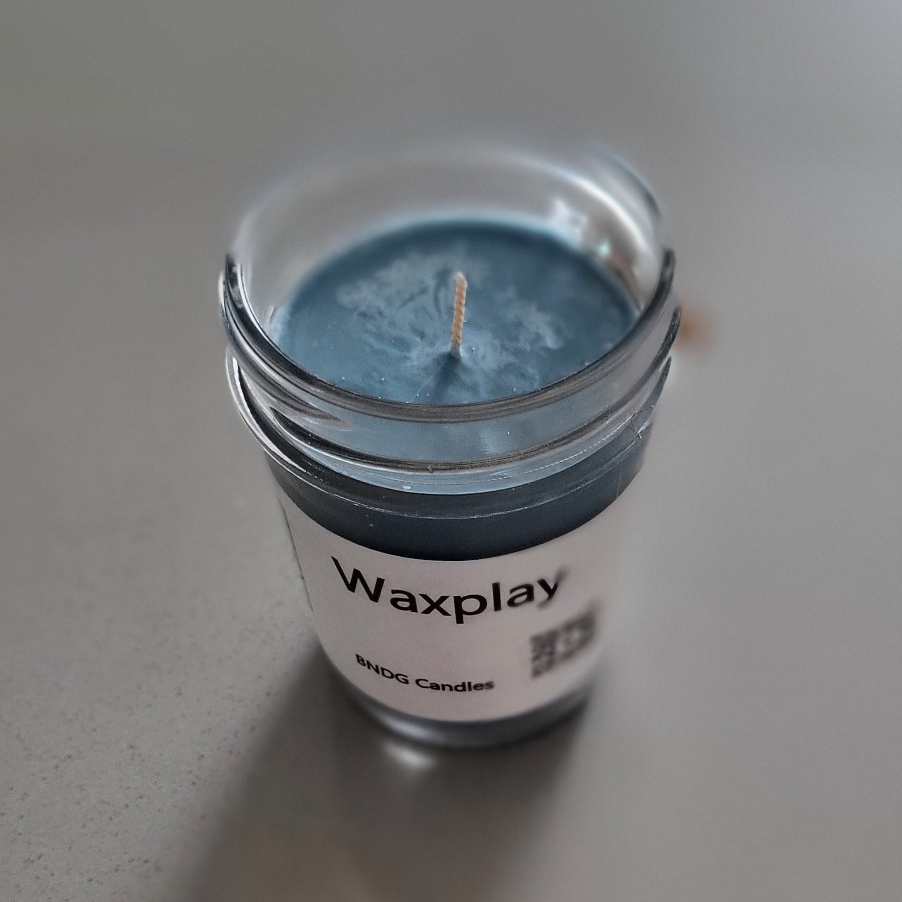 Small container of blue wax with a visible brand label on a light gray background