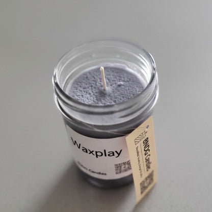 Candle in a glass jar with a label on a gray surface