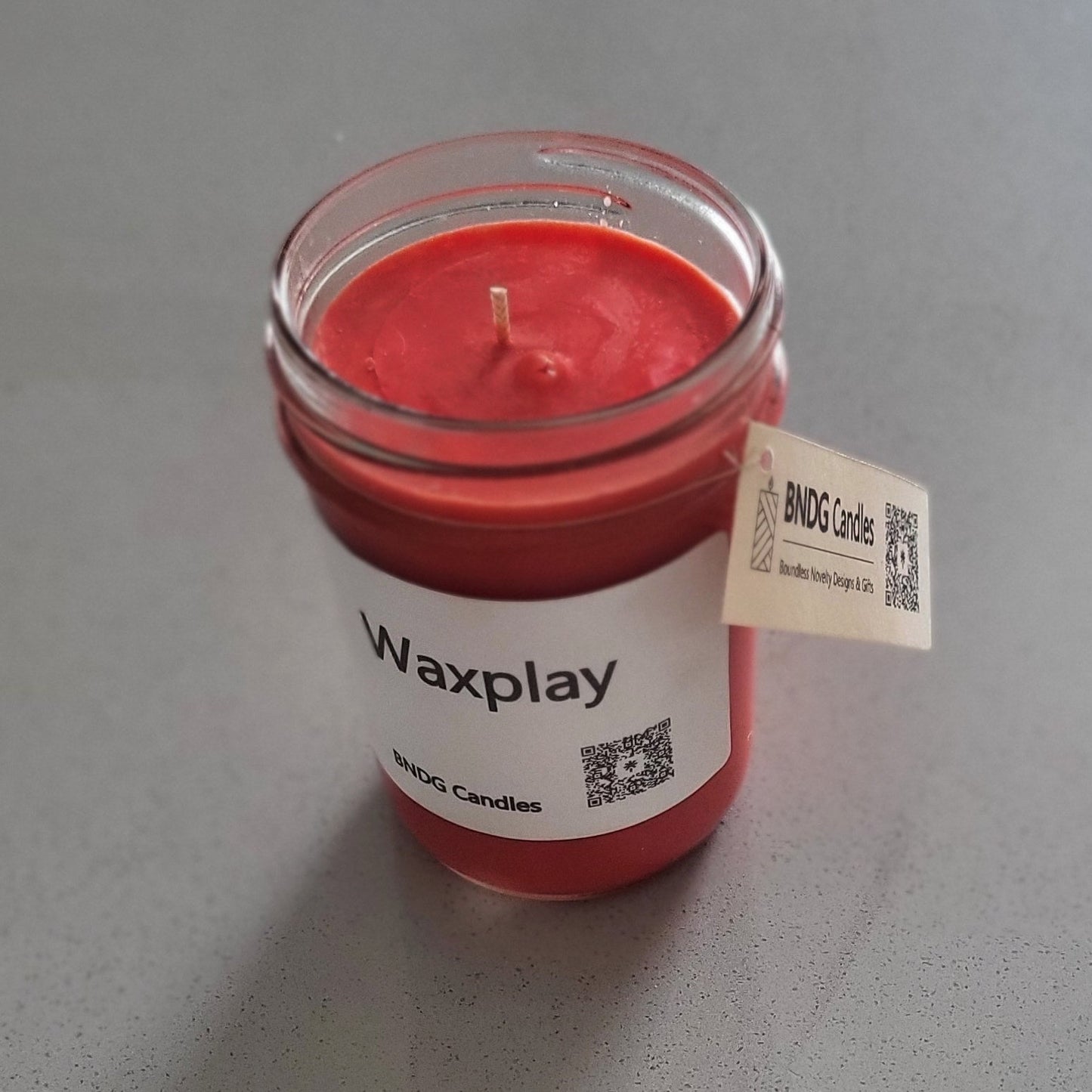 Red candle in a glass container on a gray surface